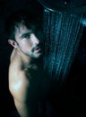 Sexy portrait of handsome naked man with beard and blue eyes under a rainfall shower looking at camera