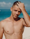 Sexy portrait of handsome topless male model on the tropical beach