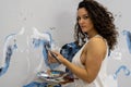 sexy pretty artist woman with curly brunette hair in white underskirt with Brush and palette panting on the wall Royalty Free Stock Photo