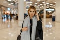 Sexy pretty stylish young blond woman with gray eyes in a luxurious gray coat with a vintage scarf with a fashionable bag Royalty Free Stock Photo