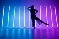 Sexy pretty young woman dancer dancing and posing in a room with bright neon blue purple color. Silhouette of a sports Royalty Free Stock Photo