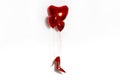 Sexy red high-heeled shoe hangs on red heart-shaped balloons. Valentine\'s day Royalty Free Stock Photo