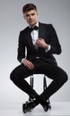 seated elegant man fixing black suit collar
