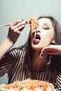 seductive cheeky girl with plate of pasta and fork wildly eats pasta with ketchup