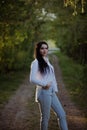 Sexy sensual brunette walks in a summer forest at sunset in a white blouse and jeans Royalty Free Stock Photo