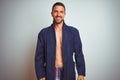 Sexy shirtless man wearing comfortable pajamas and robe over isolated background with a happy and cool smile on face