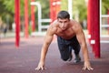 Shirtless muscular young man doing push-ups on the outdoors background. Exercise concept. Copy space. Royalty Free Stock Photo
