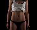 slim fit woman body. Muscled abdomen. Sportswear. Dark back Royalty Free Stock Photo