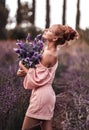 Sexy slim red-haired woman in jumpsuit with shorts stands in the middle of field holding bouquet of wildflowers lavender Royalty Free Stock Photo