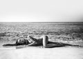 Sexy slim woman girl is lying on the beach sand on th background of the sea during vacation on seashore. Black and white Royalty Free Stock Photo