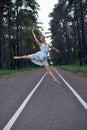 Sexy Slim Young Caucasian Ballet Dancer in Light Blue Tutu Posing in Jumping Dance Pose During Ballet Pas in Summer Forest With Royalty Free Stock Photo