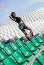 sport girl posing at stadium. Fitness girl with a sports figure in leggings and black top standing on the seat in the stadium