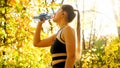 Sexy sporty woman with ponytail drinking water in autumn park Royalty Free Stock Photo