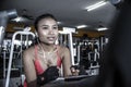 and sweaty Asian woman training hard at gym using elliptical pedaling machine gear in intense workout