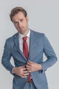 Sexy unshaved man buttoning blue suit in a confident manner