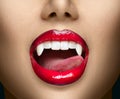 Sexy Vampire Woman`s red bloody lips close-up. Vampire girl licking fangs with tongue. Fashion Glamour Halloween Royalty Free Stock Photo