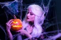 Sexy witch with hallowen makeup and long white hair holding pumpkin on black background Royalty Free Stock Photo