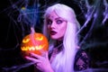 Sexy witch with hallowen makeup and long white hair holding pumpkin on black background Royalty Free Stock Photo