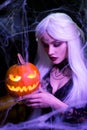 Sexy witch with hallowen makeup and long white hair holding pumpkin on black background Royalty Free Stock Photo