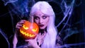 Sexy witch with hallowen makeup and long white hair holding pumpkin on black background Royalty Free Stock Photo