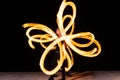 sexy woman artist perform fiery twirly trails by spinning flaming pois during fire performance