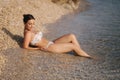 Sexy woman in bikini on the beach enjoying summer sun. Beautiful woman lies near the sea. Water wets her feet Royalty Free Stock Photo