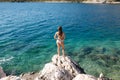 Sexy woman in bikini stand on the rock by the sea. Beautiful lagoon. Woman enjoying summer sun. Back view of sexy woman Royalty Free Stock Photo