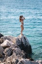 Sexy woman in bikini stand on the rock by the sea. Beautiful lagoon. Woman enjoying summer sun. Back view of sexy woman Royalty Free Stock Photo