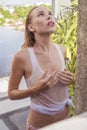 woman in bikini and white tank top taking outdoors shower on the rooftop Royalty Free Stock Photo