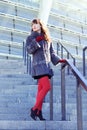 woman in a black dress, red tights and a fur coat