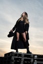 Sexy woman in black fashion coat, hat and black shoes boots. Stylish fashion woman posing outdoor. Attractive young