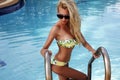 woman with blond hair in bikini and sunglasses posing in swimming pool Royalty Free Stock Photo