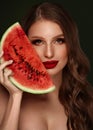 Sexy woman with curls, classic make-up and red lips holds a watermelon in her hands. Beauty face.
