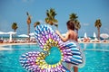 woman holding inflated buttfly float in front of blue swimming pool