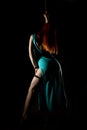 woman pole dancer in a long turquoise dress with a slit on a dark background Royalty Free Stock Photo