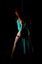 woman pole dancer in a long turquoise dress with a slit on a dark background Royalty Free Stock Photo