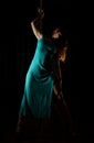 woman pole dancer in a long turquoise dress with a slit on a dark background Royalty Free Stock Photo