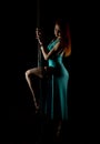 woman pole dancer in a long turquoise dress with a slit on a dark background Royalty Free Stock Photo