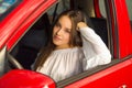 woman posing for camera while her arm is over the window of her red car Royalty Free Stock Photo