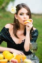 Sexy woman with red lips, stylish makeup on beautiful face squeezing juice from fresh orange. Outdoor fashion photo of Royalty Free Stock Photo