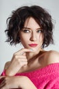 woman with short hair cut in pink red sweater on white background. Perfect girl with wet tousled dark hair and bright makeup Royalty Free Stock Photo
