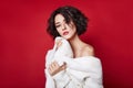 woman with short hair cut in white sweater on red background. Perfect girl with wet tousled dark hair and bright makeup, Royalty Free Stock Photo