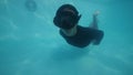 Sexy woman swimming underwater in a pool showing toungue and making peace sign. Active and happy woman concept.