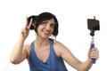 woman taking selfie photo with stick and mobile phone camera posing happy Royalty Free Stock Photo