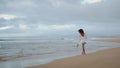 Sexy woman walking ocean coastline alone. Happy carefree girl touching sand