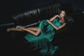 Woman wearing beautiful green silk dress is posing on leather couch Royalty Free Stock Photo