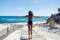 Sexy woman wearing bikini on the beach. Young female in swimsuit standing on the seashore with her hands raised. Royalty Free Stock Photo