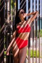 woman wearing red bikini swimsuit and sunglasses standing on the near swimming pool with artistic shadow pattern on Royalty Free Stock Photo