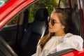 woman wearing sunglasses and posing for camera while her arm is over the window of her red car Royalty Free Stock Photo