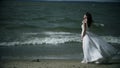 woman in a white dress stands on sea. Dress flutters in wind slow motion.